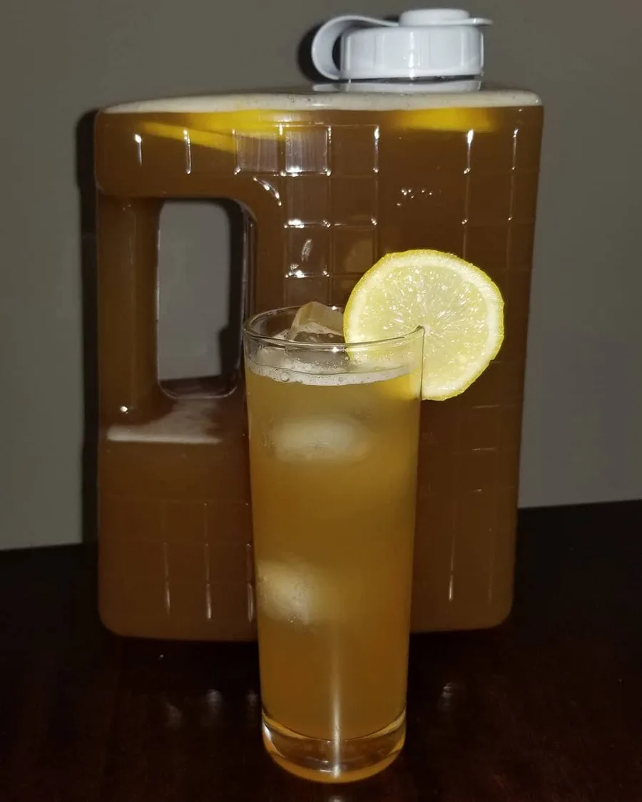 Dirty Lemonade cocktail served over ice with a lemon wheel beside a bottled batch