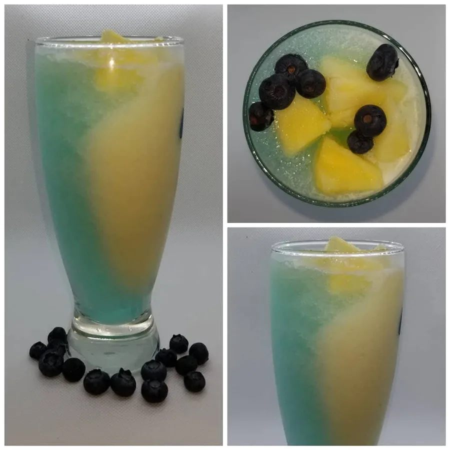 Jack Frost cocktail shown from the side and above with pineapple and blueberries