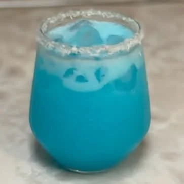 Blue Winter Wonderland cocktail served over ice in a coconut-rimmed glass